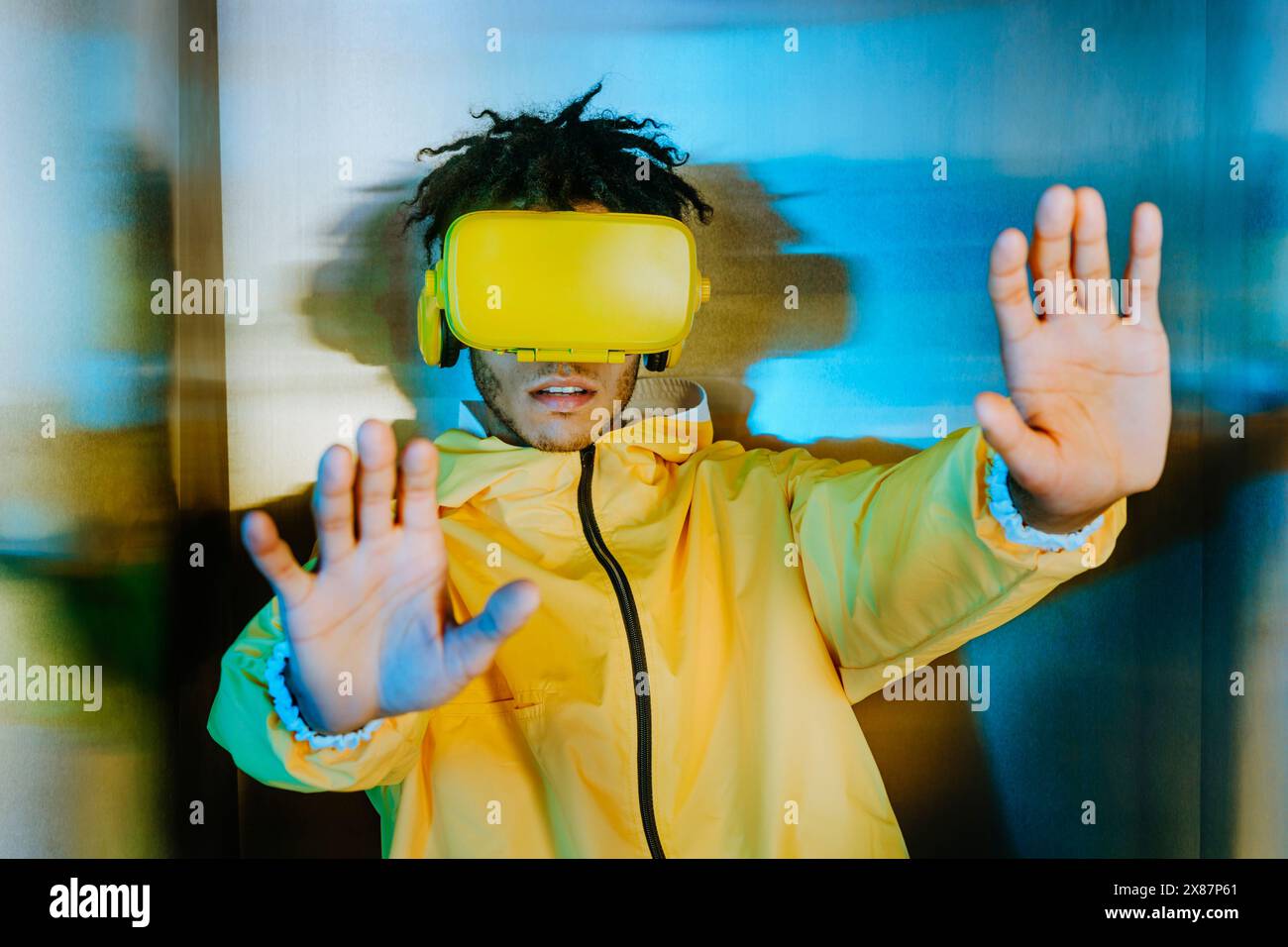 Giovane uomo che indossa un visore per la realtà virtuale e mostra le palme Foto Stock