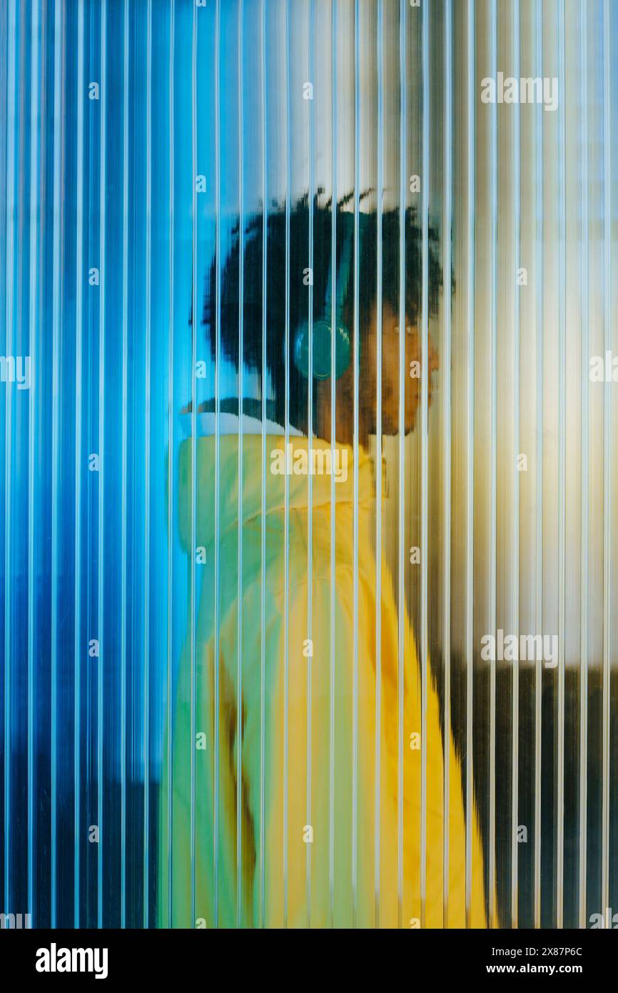 Giovane uomo con cuffie dietro un muro futuristico Foto Stock