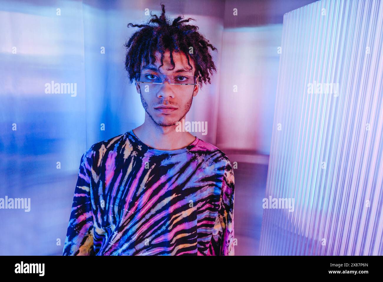 Uomo serio con casuali colorati vicino a sfondo illuminato Foto Stock