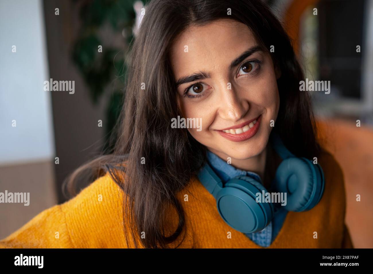 Giovane donna sorridente con le cuffie wireless bluetooth Foto Stock