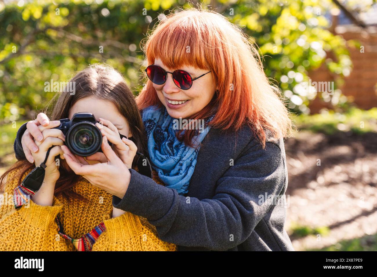 Madre felice che insegna fotografia a figlia attraverso la macchina fotografica Foto Stock
