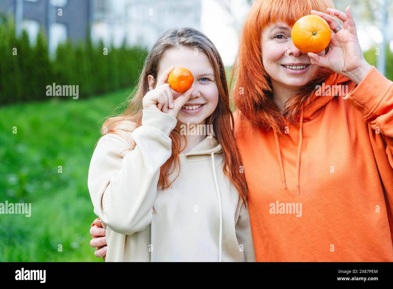 Madre e figlia felici che tengono le arance in faccia Foto Stock