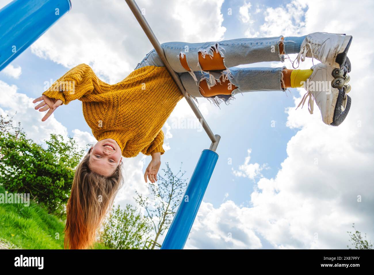 Ragazza felice appesa al rovescio sotto il cielo nuvoloso Foto Stock