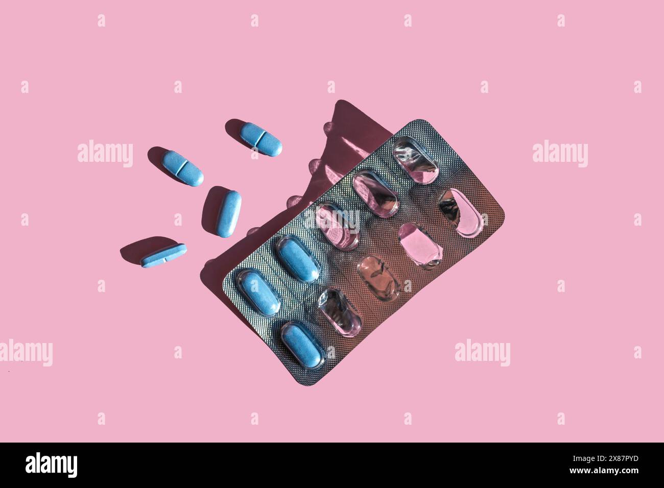 Pillole blu e confezione blister su sfondo rosa Foto Stock