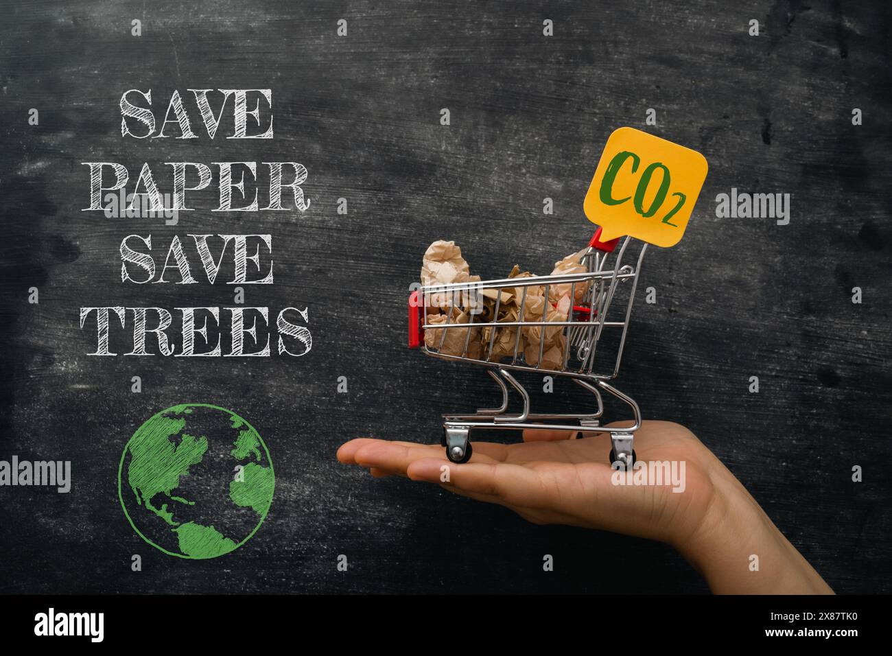 Una mano che regge un carrello con un cartello con la scritta Save Paper Save Trees Foto Stock