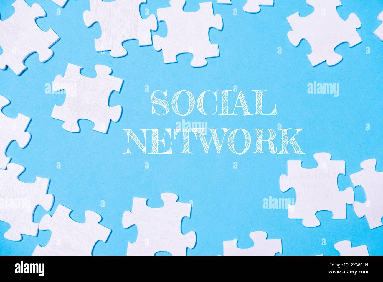 Un puzzle con la parola social network scritta sopra. I pezzi del puzzle sono sparsi nell'immagine, creando un senso di disordine e complessità Foto Stock