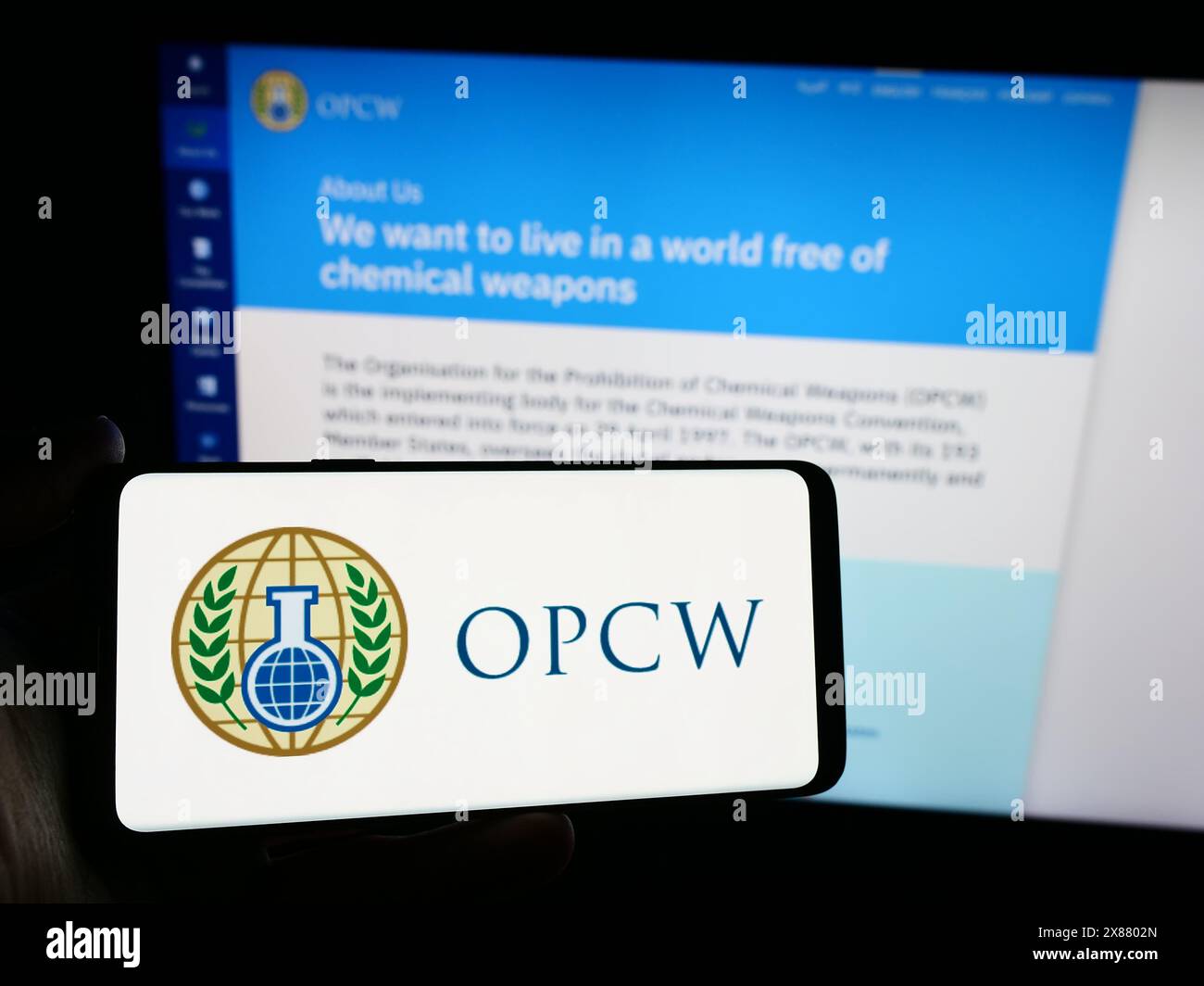 Persona che possiede uno smartphone con il logo dell’Organizzazione per la proibizione delle armi chimiche (OPCW) davanti al sito web. Mettere a fuoco il display del telefono. Foto Stock