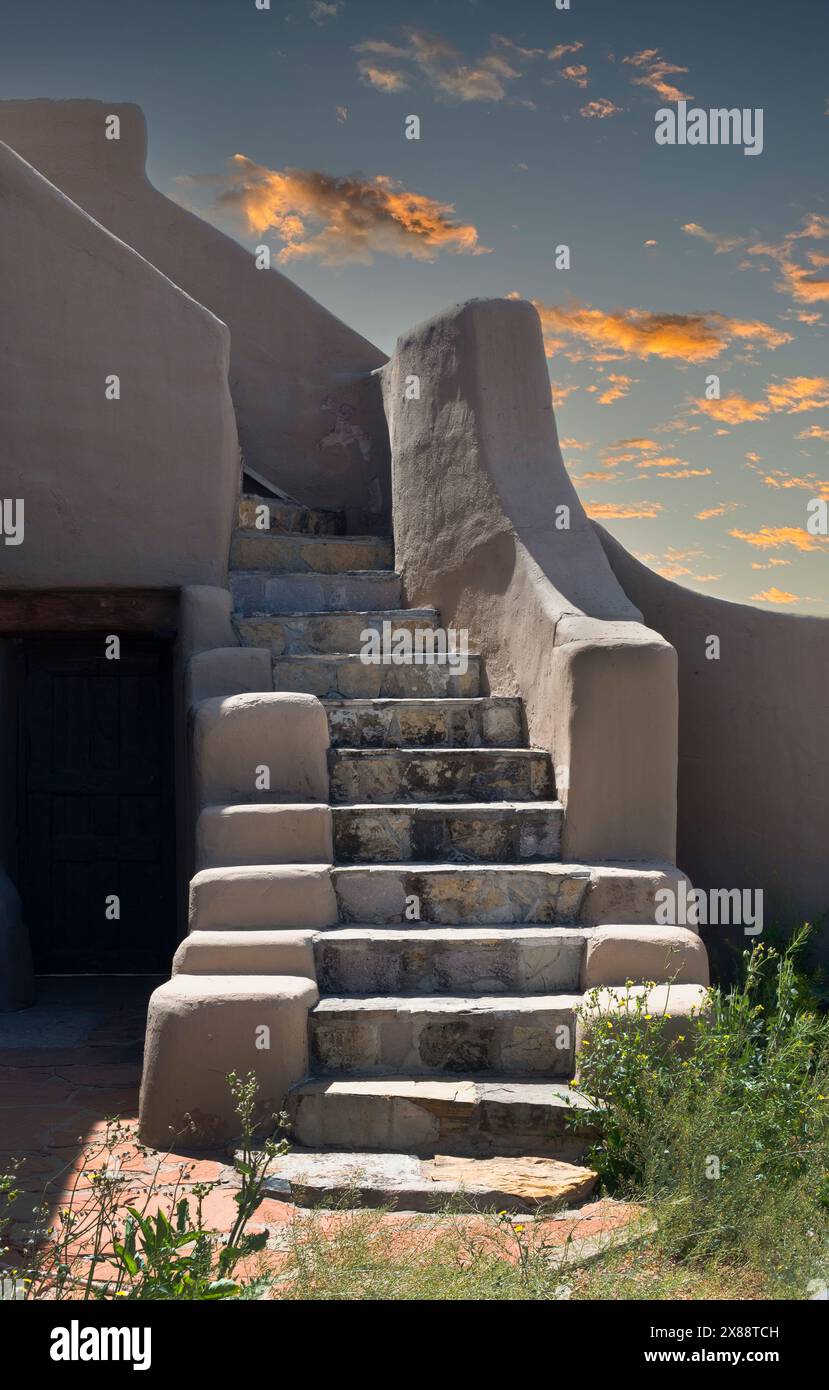 Gradini di piastrelle sbiadite che conducono verso l'alto a un'abitazione realizzata con stucco rustico in stile adobe contro un tramonto con nuvole sparse a Las Cruces, NEW MEXICO, USA Foto Stock