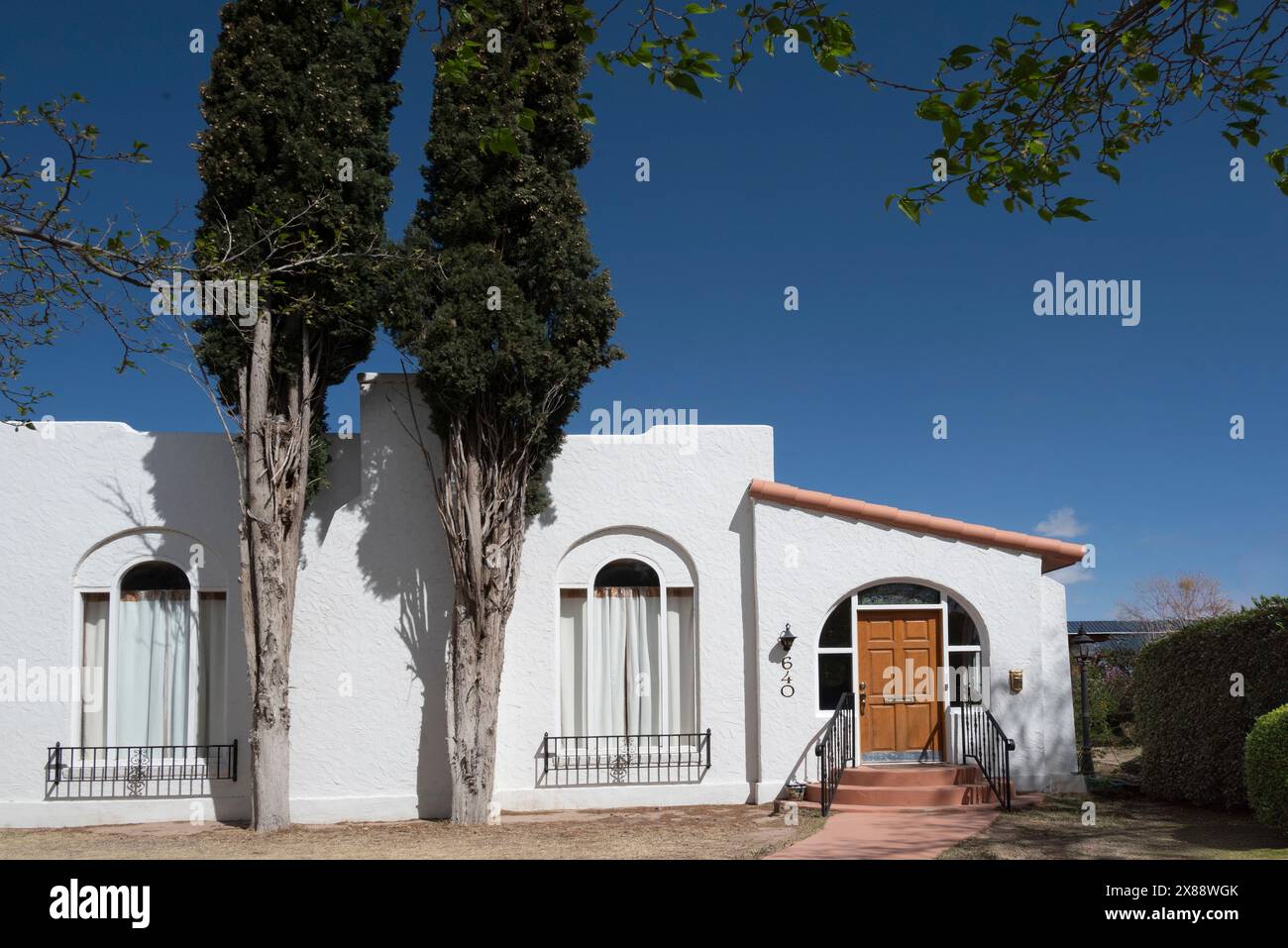 Graziosa casa in stucco bianco con elementi in stile revival pueblo, finestre in stile art deco con dettagli MCM e alti cipressi a Las Cruces, NEW MEXICO Foto Stock