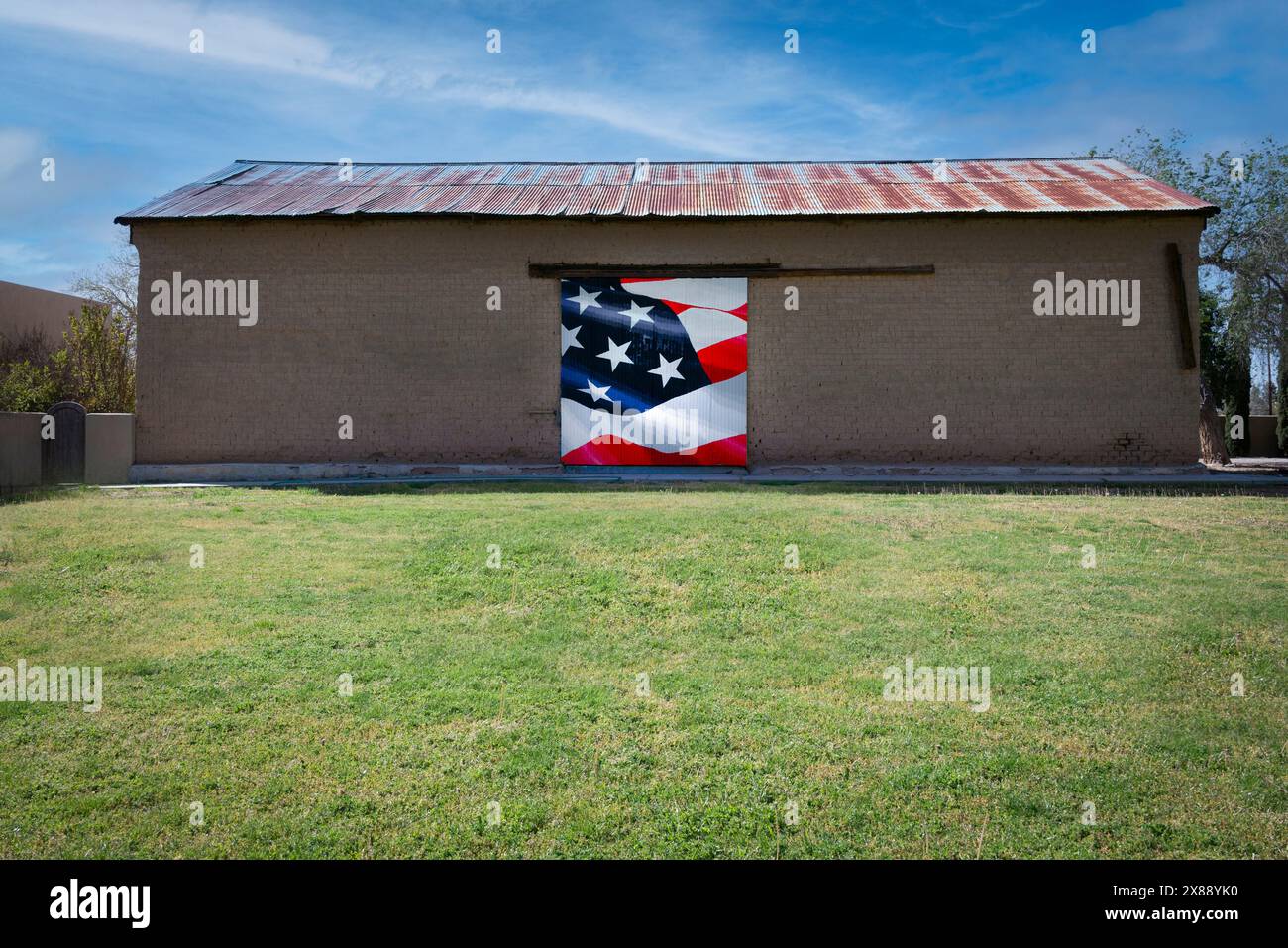 Un albergo verde con un vecchio edificio in mattoni con un tetto in stagno arrugginito che mostra un pezzo della bandiera americana, un dettaglio in rosso, bianco e blu Foto Stock