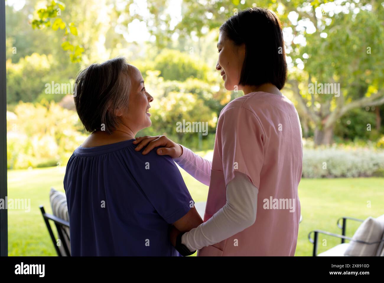 All'aperto, giovane infermiera asiatica, paziente di mezza età sorridente Foto Stock