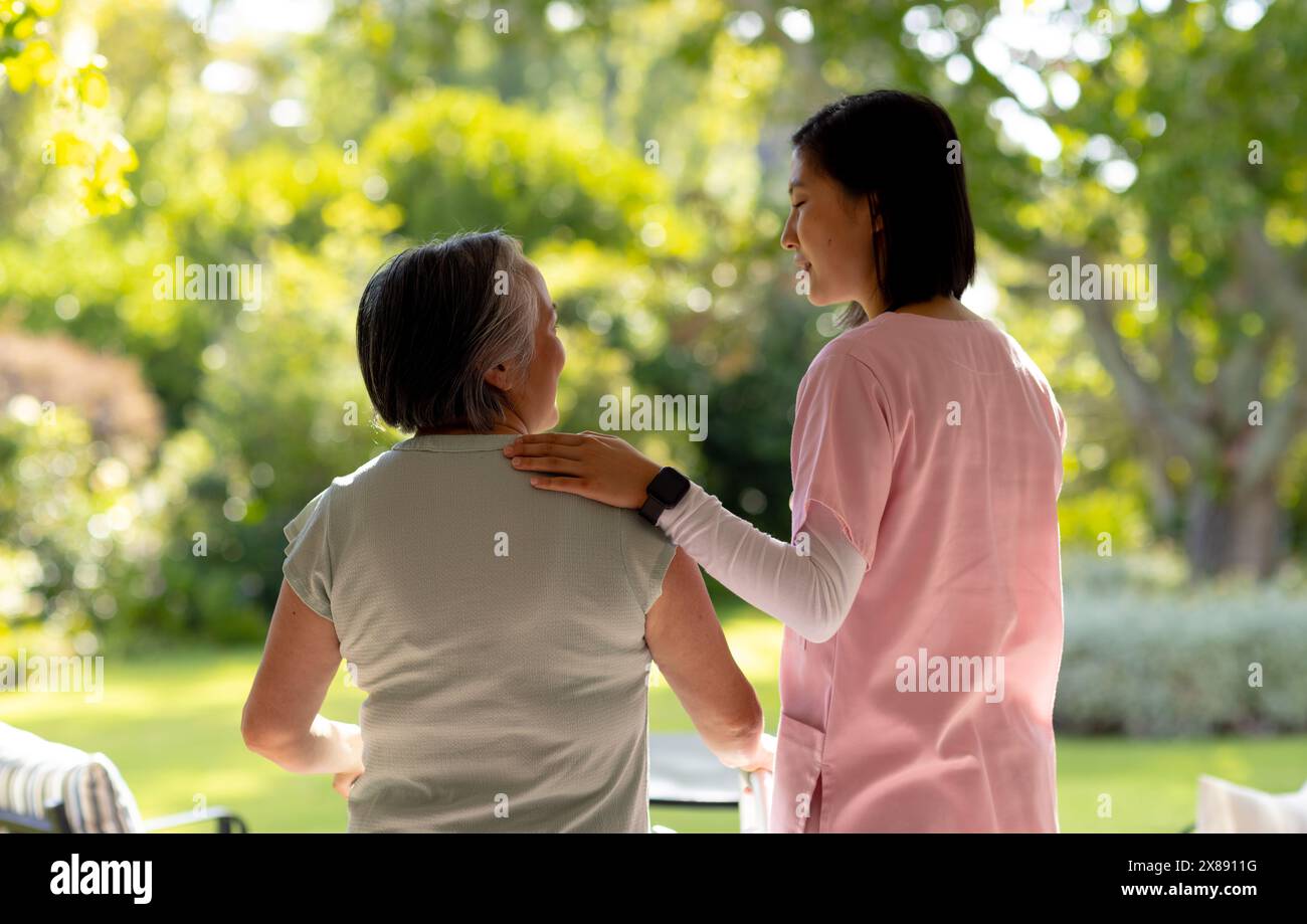 Giovane infermiera asiatica e paziente di mezza età all'aperto in abiti casual Foto Stock