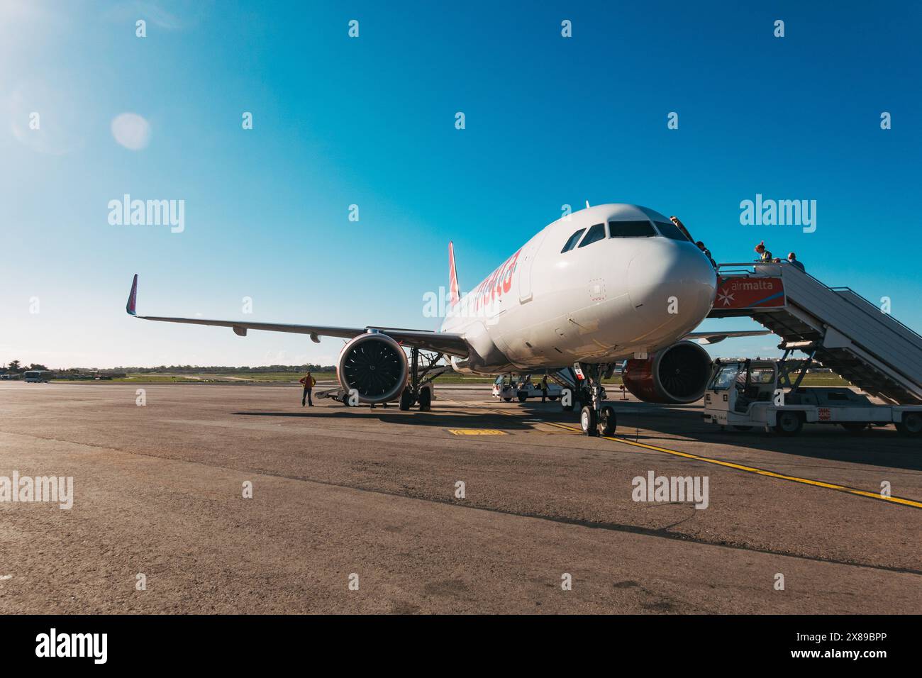 I passeggeri saliranno a bordo di un AirMalta A320 tramite le scale sull'asfalto dell'aeroporto internazionale di Malta, in un pomeriggio di sole Foto Stock