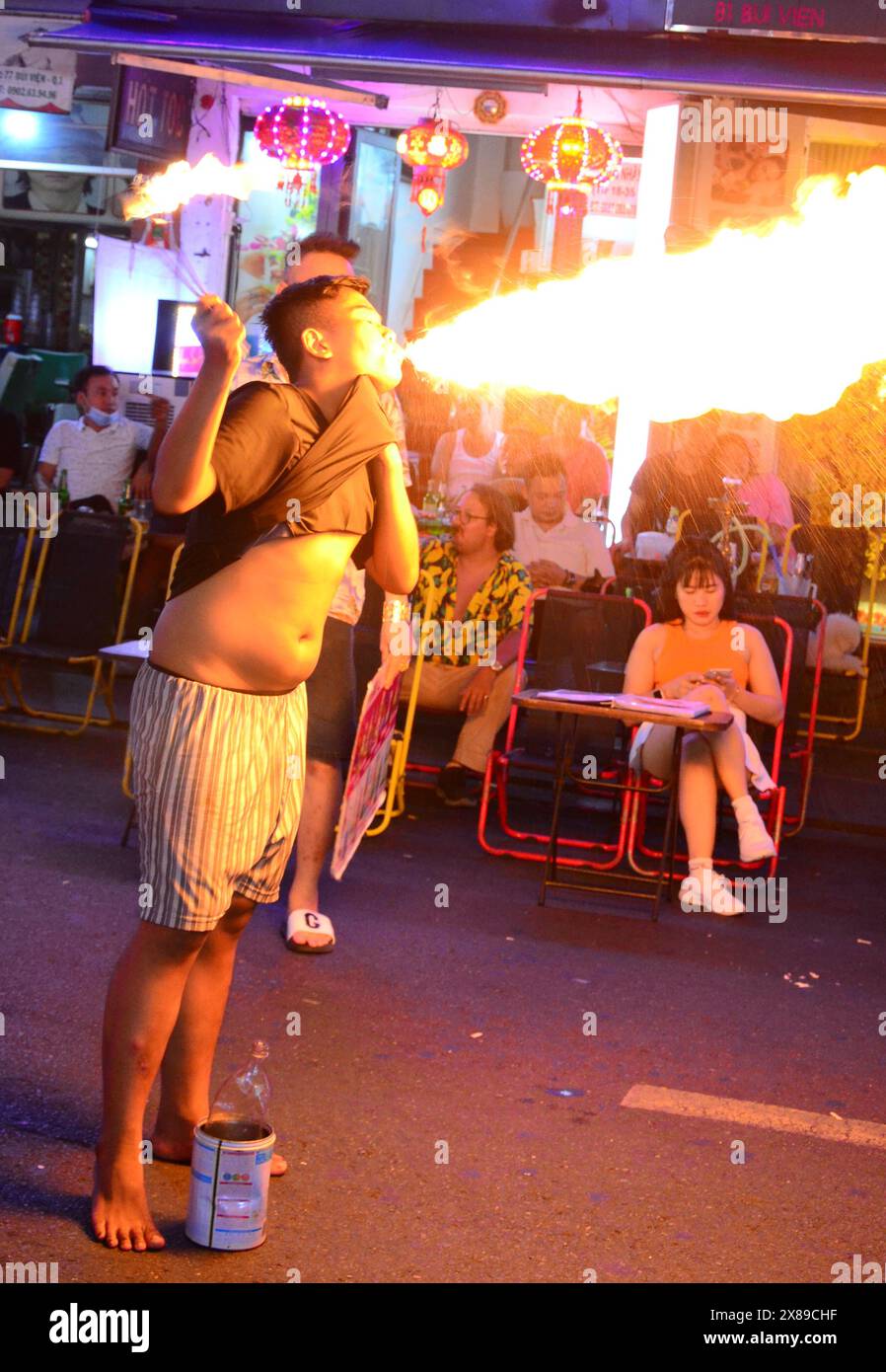 Vita quotidiana a ho chi Minh City, che era chiamata Saigon, in Vietnam, Asia. Vita notturna su Walking Street Saigon, chiamata anche Bui Vien Street, la strada principale della cosiddetta 'zona per backpackers' di ho chi Minh City. Un giovane uomo o adolescente lancia fiamme dalla bocca, mangia il fuoco o respira il fuoco, per sollecitare consigli ai visitatori. I giovani usano cherosene per fare fiamme e possono bruciare la bocca o ingoiare cherosene o paraffina. Foto Stock