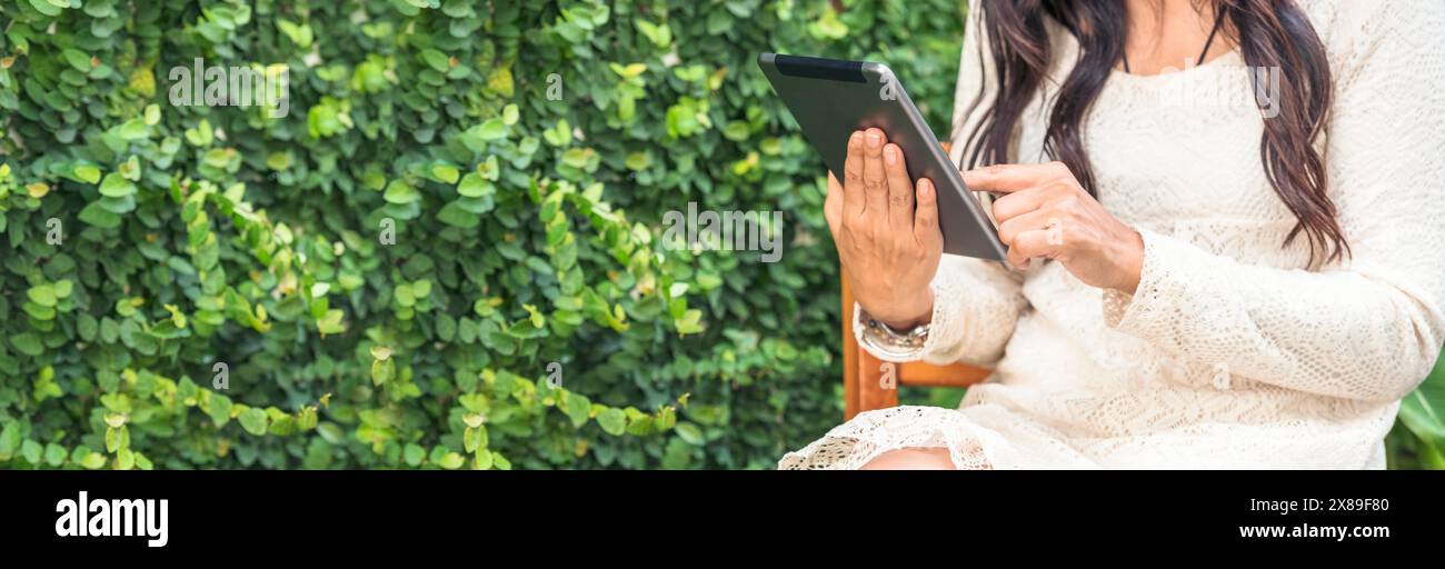 Donna asiatica che usa un tablet intelligente che fa acquisti online su smartphone con la faccia sorridente. Felicità donna asiatica che tiene il cellulare che controlla la posta da onl Foto Stock
