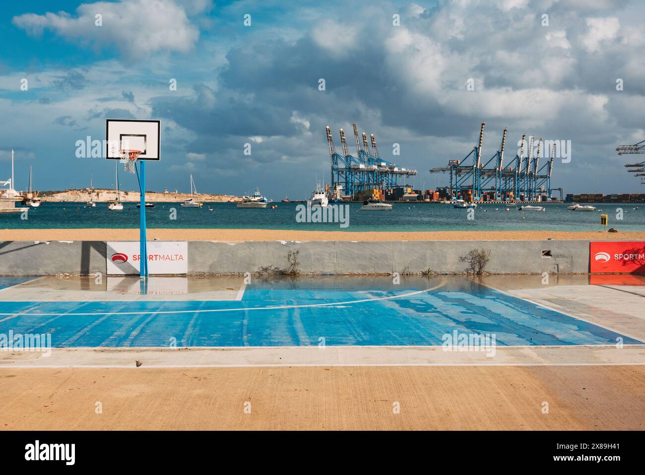 Un campo da basket vuoto e umido dopo che le nuvole di pioggia hanno attraversato Birżebbuġa, Malta Foto Stock