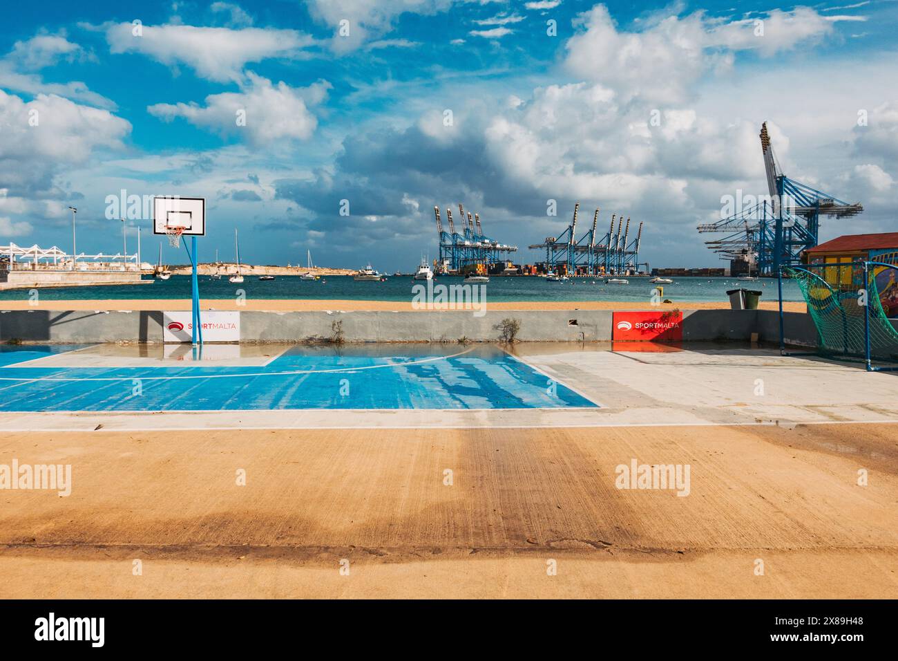 Un campo da basket vuoto e umido dopo che le nuvole di pioggia hanno attraversato Birżebbuġa, Malta Foto Stock