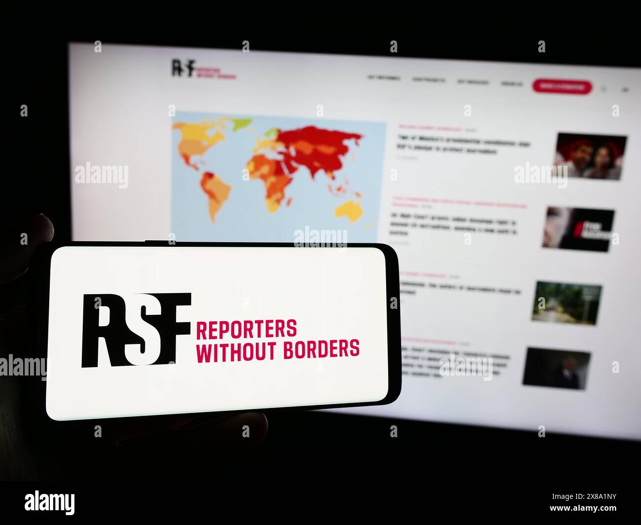 Persona che possiede uno smartphone con il logo dell'organizzazione internazionale Reporter senza frontiere davanti al sito web. Mettere a fuoco il display del telefono. Foto Stock