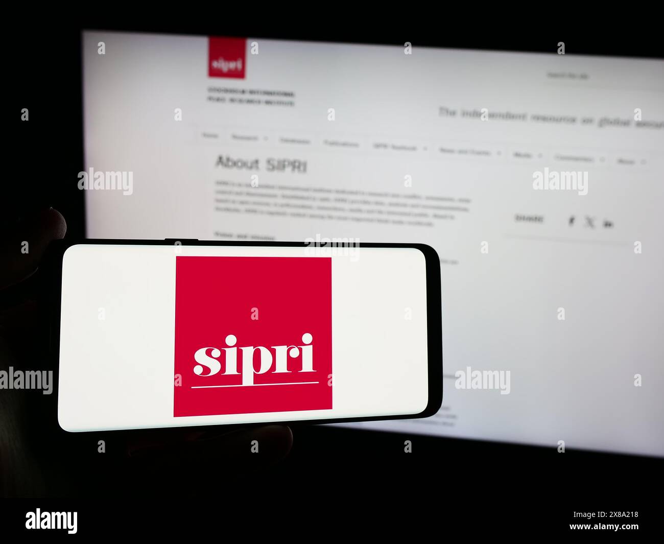 Persona con smartphone con logo dell'Istituto internazionale di ricerca sulla pace di Stoccolma (SIPRI) davanti al sito Web. Mettere a fuoco il display del telefono. Foto Stock