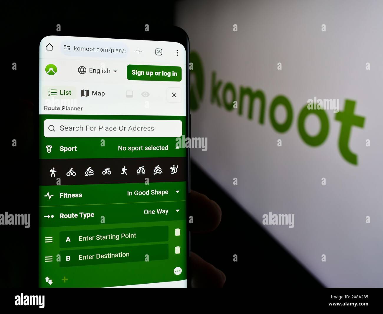 Persona che possiede uno smartphone con pagina web dell'app tedesca di pianificazione del percorso komoot GmbH davanti al logo. Messa a fuoco al centro del display del telefono. Foto Stock