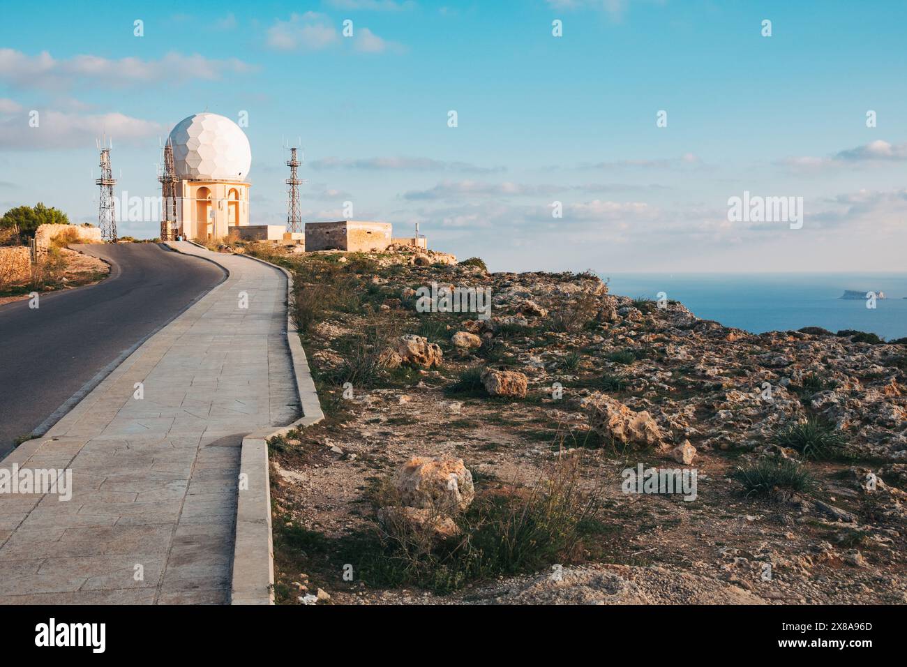 Una strada si snoda davanti a una cupola radar dell'aviazione arroccata sulla costa meridionale dell'isola di Malta nel Mar Mediterraneo Foto Stock