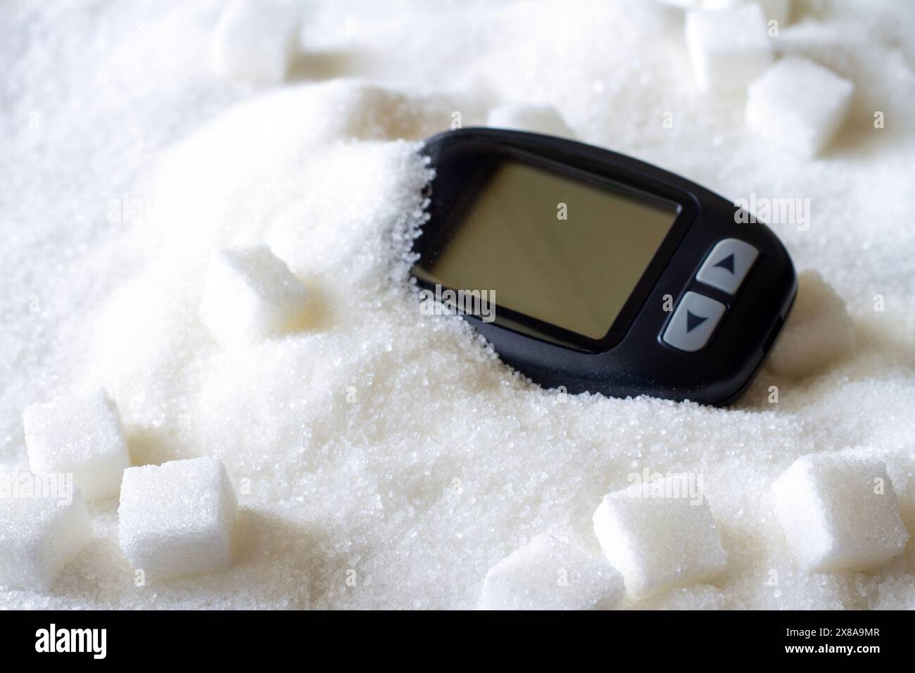 Glucometro su zucchero versato, consumo eccessivo di zucchero, concetto di diabete Foto Stock