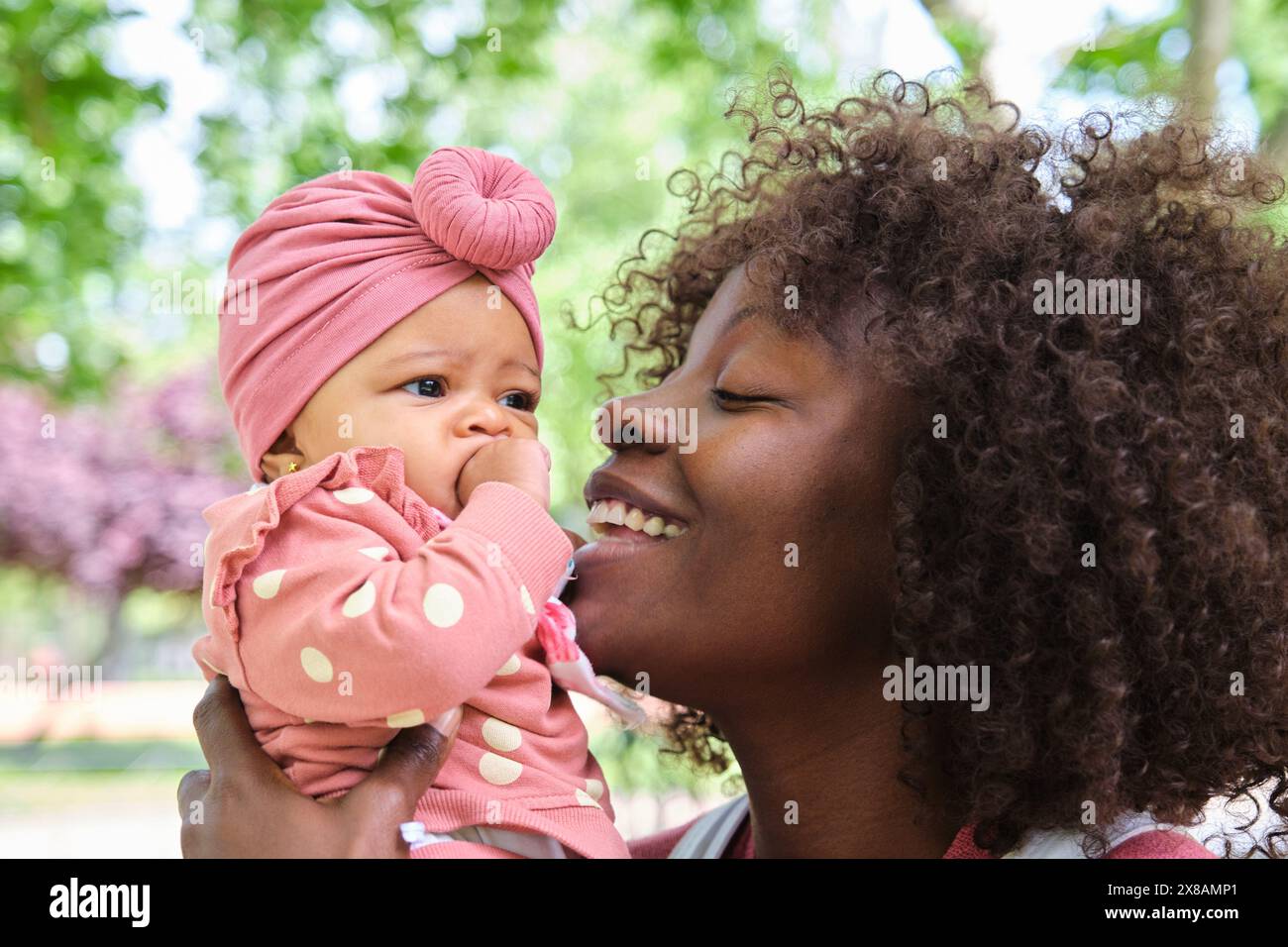 La donna africana tiene in mano una bambina e sorride. Foto Stock