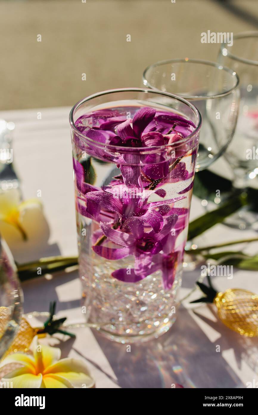 Elemento centrale della vetreria per una festa tropicale con orchidee viola Foto Stock