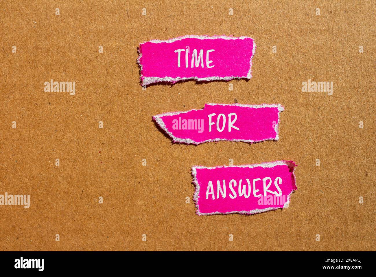 Tempo per le risposte parole scritte su pezzi di carta rosa strappati con sfondo in cartone. Simbolo tempo concettuale per le risposte. Copia spazio. Foto Stock
