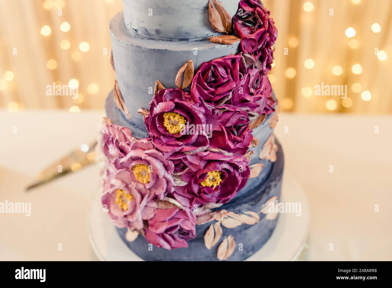 Elegante torta nuziale a tre livelli con decorazioni floreali viola Foto Stock