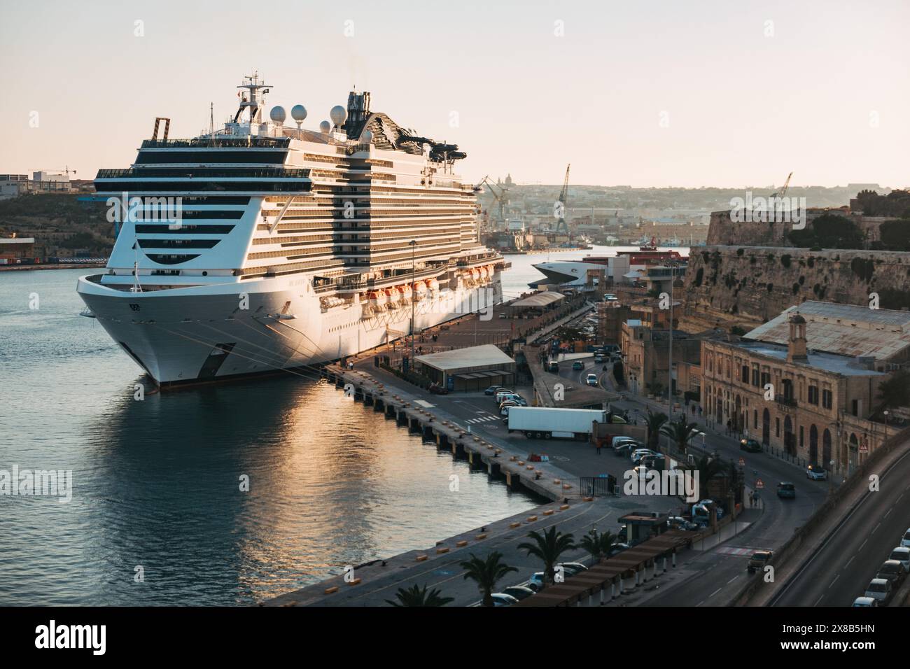 L'MSC Seaview, una grande nave da crociera, attraccata al porto di la Valletta, Malta, mentre il sole tramonta sulla città Foto Stock