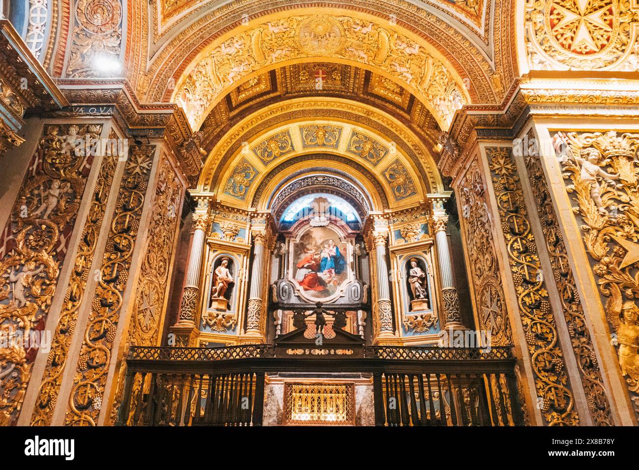 Una vista degli intricati interni della Concattedrale di San Giovanni, Malta, con un soffitto d'oro, colonne ornate e dipinti religiosi. Foto Stock
