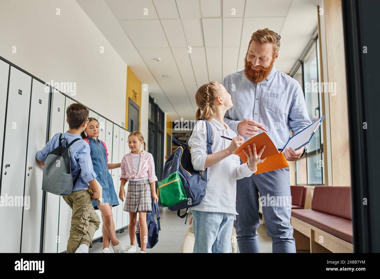 Un insegnante si erge tra un gruppo di bambini in un ambiente luminoso e vivace, coinvolgendoli in istruzione. Foto Stock