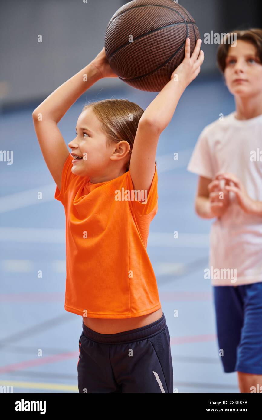 Una giovane ragazza regala con gioia un pallacanestro alto, irradiando un senso di eccitazione e passione per il gioco. Foto Stock