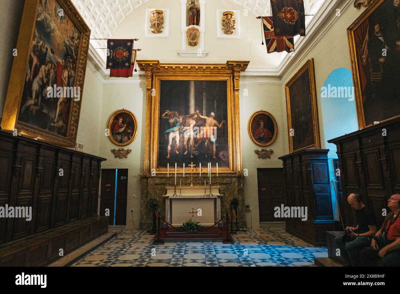 Cappella di Malta: Altare con dipinti, i visitatori osservano opere d'arte, circondata da altri dipinti e armadi in legno nella concattedrale di San Giovanni, Malta Foto Stock