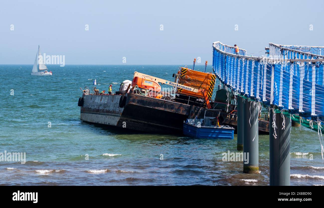 Timmendorfer Strand, Germania. 24 maggio 2024. Un pontone che è stato strappato si trova nel Mar Baltico a Timmendorfer Strand sul molo. I lavori hanno iniziato a recuperare la piattaforma di lavoro a cuneo, che si era rotta in forti onde. Credito: Daniel Bockwoldt/dpa/Alamy Live News Foto Stock