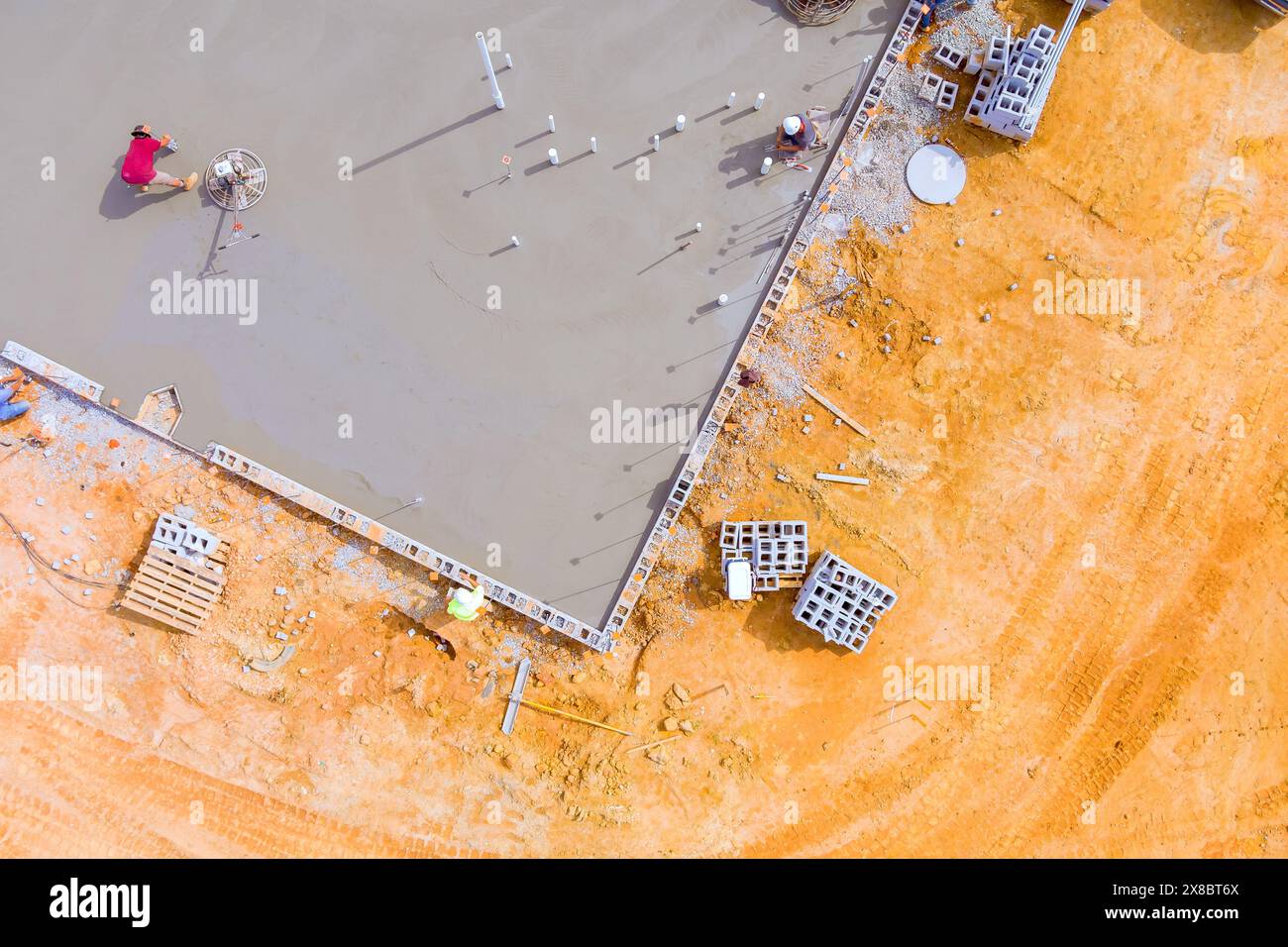 Dopo aver versato il calcestruzzo su fondamenta bagnate, mason lucida il calcestruzzo utilizzando una macchina per la lucidatura del calcestruzzo. Foto Stock