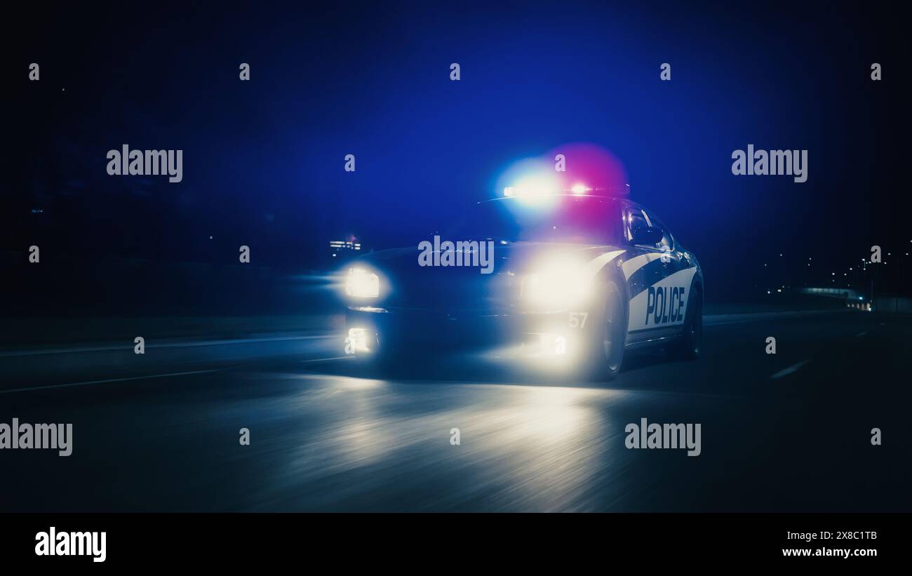 La pattuglia del traffico è all'inseguimento, guidando velocemente con le sirene che spaccano per le strade della città. Agenti della legge che inseguono un sospetto. I poliziotti in Squad Car reagiscono alla chiamata di emergenza. Night Shot cinematografico Foto Stock