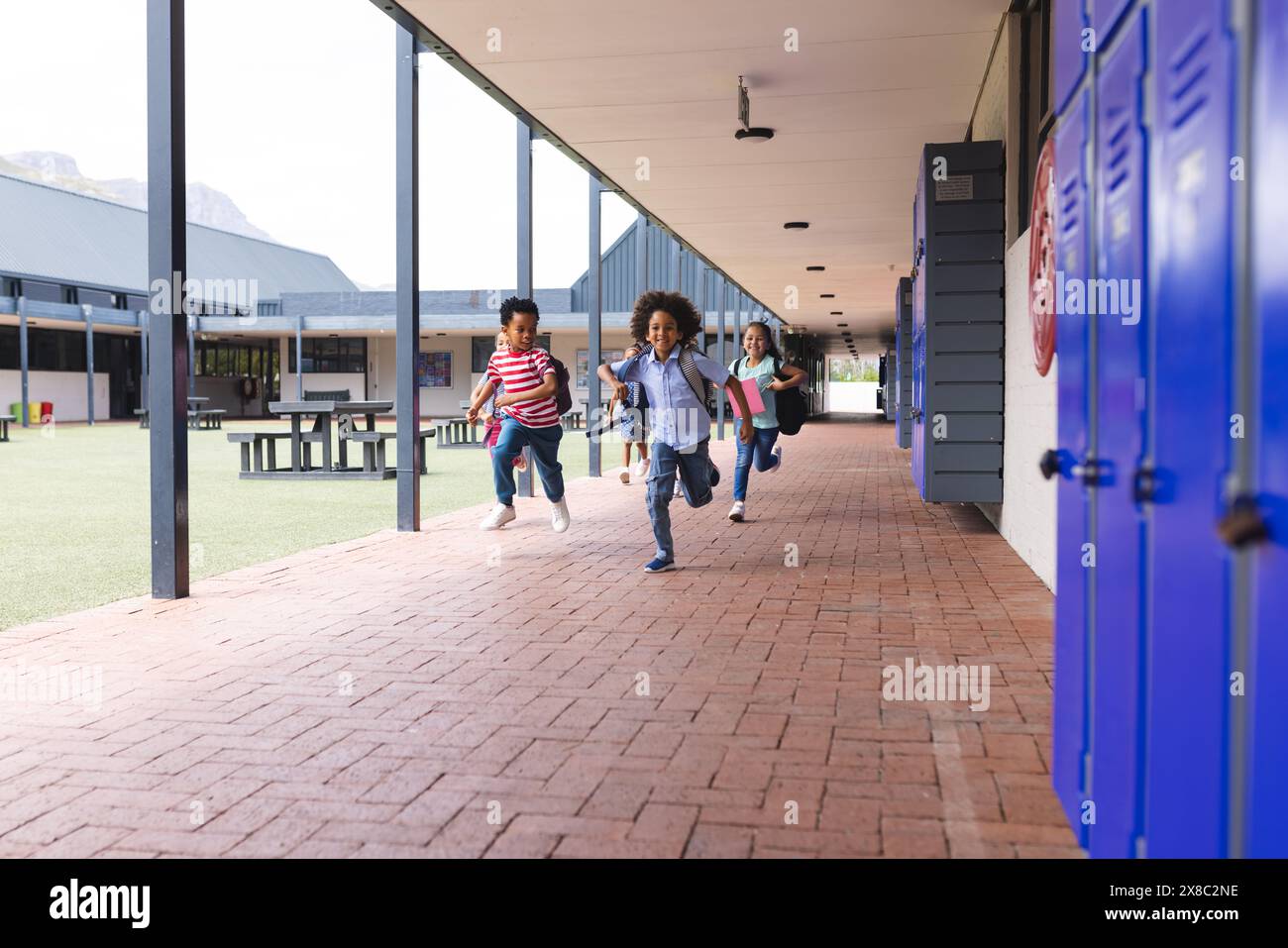 A scuola, diversi bambini corrono nel corridoio con spazio per le copie all'aperto Foto Stock