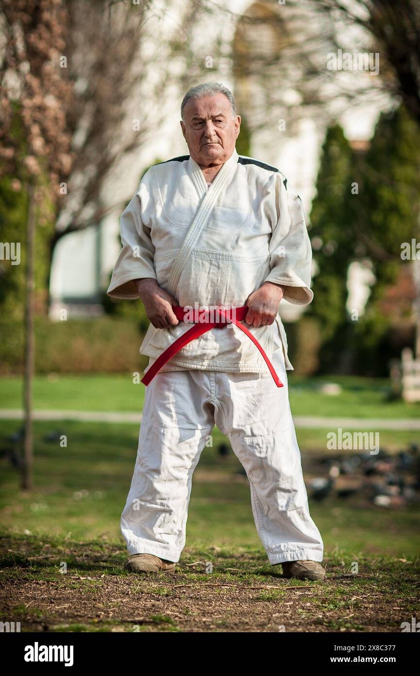 Il tutore della cintura rossa. Un maestro di arti marziali in una tuta di karate presenta con orgoglio una vivace cintura rossa, che simboleggia il successo e la competenza nella sua arte Foto Stock