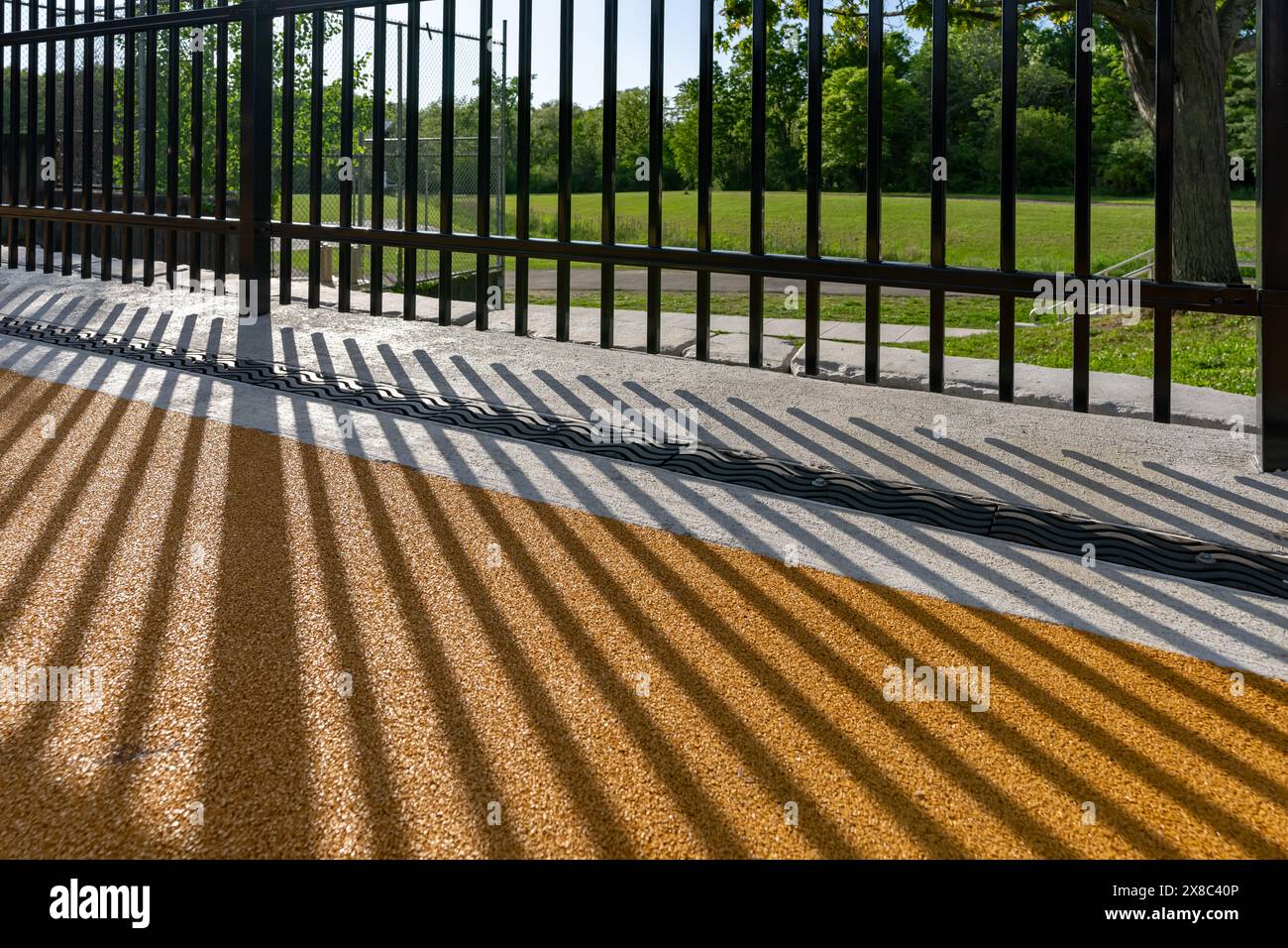 Immagine nel tardo pomeriggio di uno scarico di trincee in metallo ornamentale in cemento con motivo ombra da una recinzione ornamentale adiacente. Foto Stock