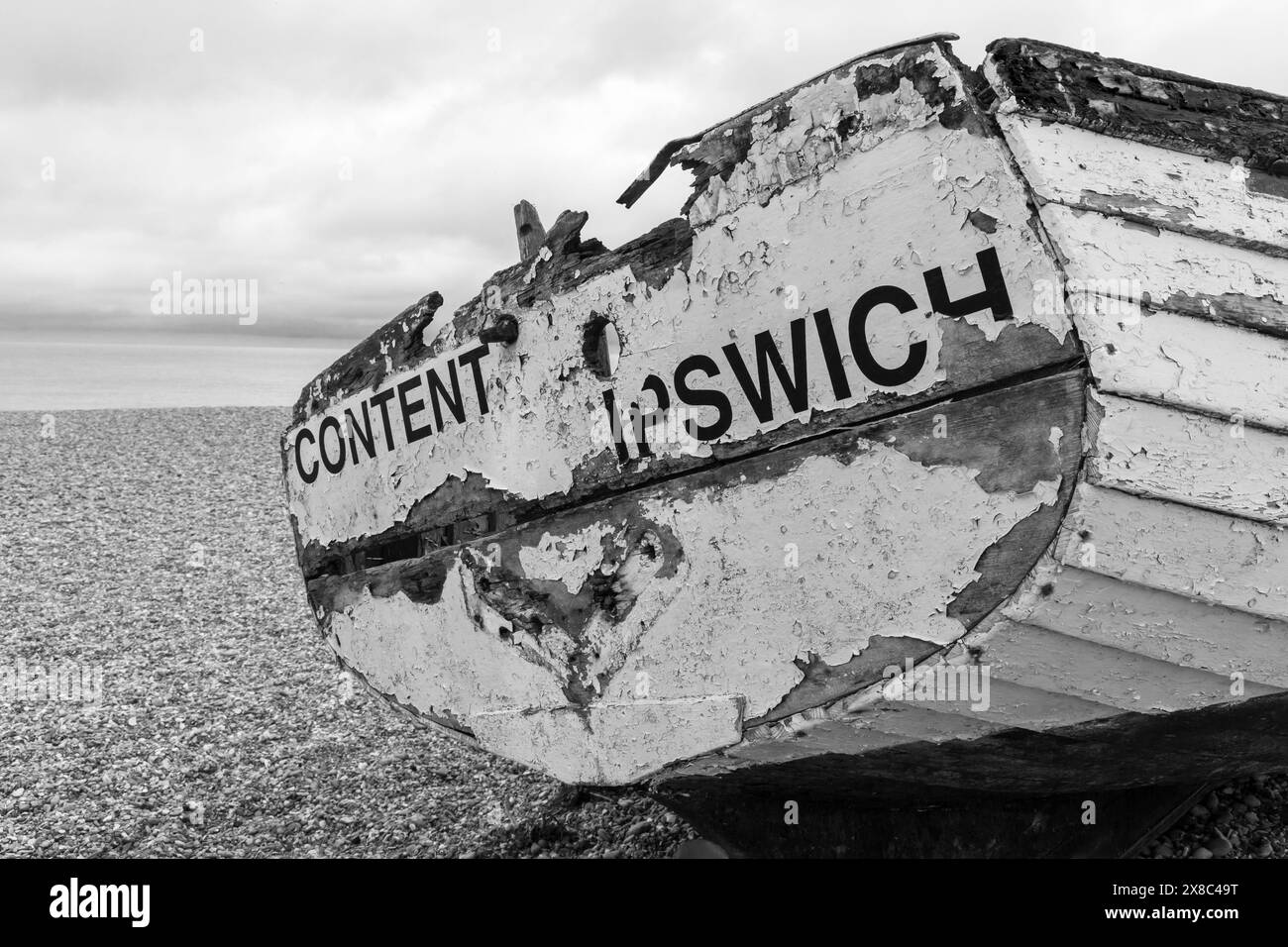 Vecchia barca sulla spiaggia di Aldeburgh, Suffolk, Regno Unito ad aprile - monocromatico bianco e nero Foto Stock