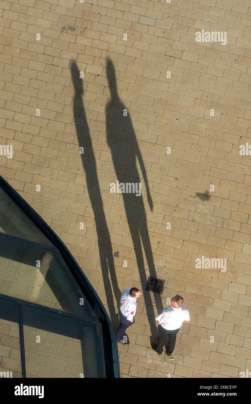 Vienna: 2 uomini che parlano, lunghe ombre, dall'alto in 22. Donaustadt, Vienna, Austria Foto Stock