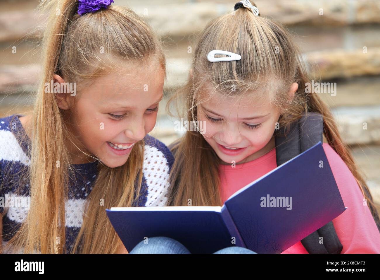 allegra ragazze delle scuole elementari che seguono un taccuino che studiano sedute sulle scale Foto Stock