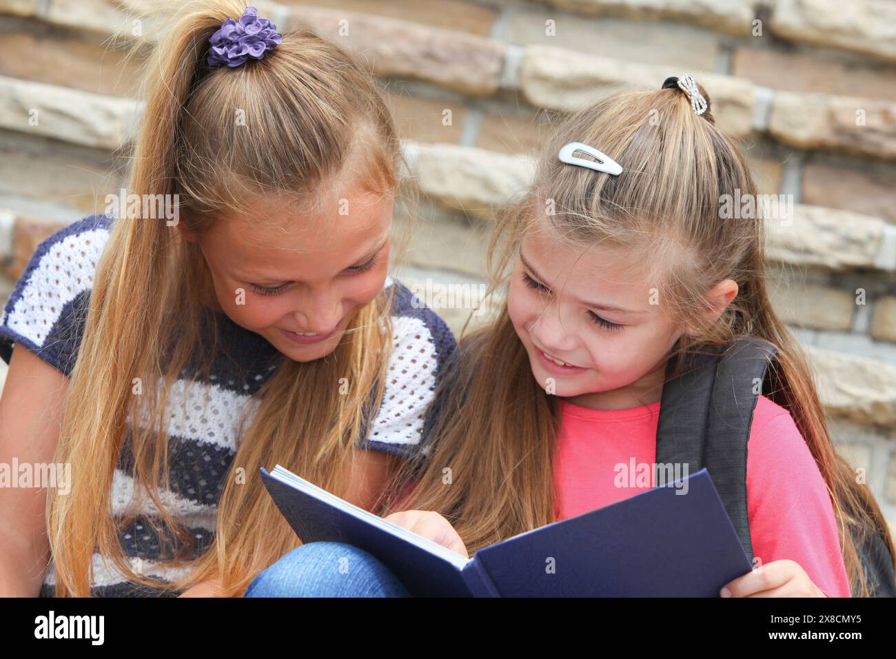 allegra ragazze delle scuole elementari che seguono un taccuino che studiano sedute sulle scale Foto Stock