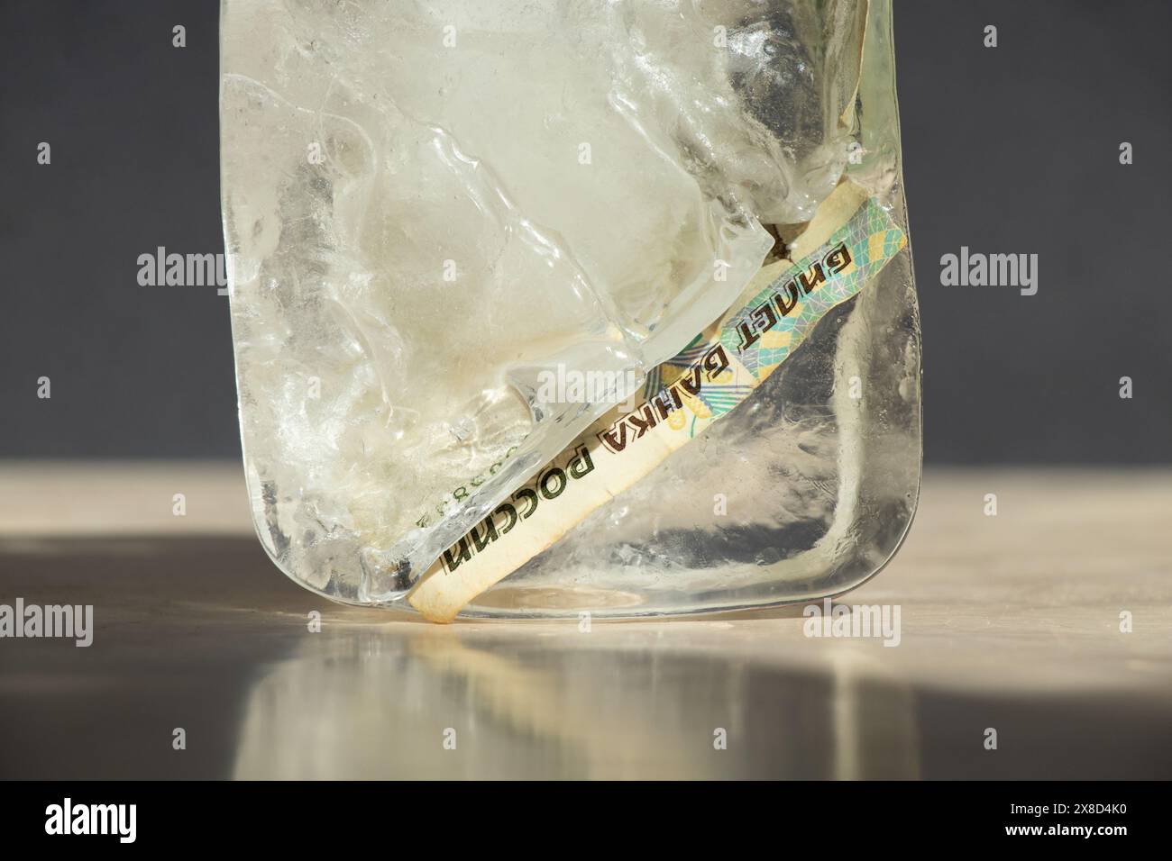 Dieci rubli russi in un cubo di ghiaccio da vicino, soldi russi congelati, sanzioni Foto Stock