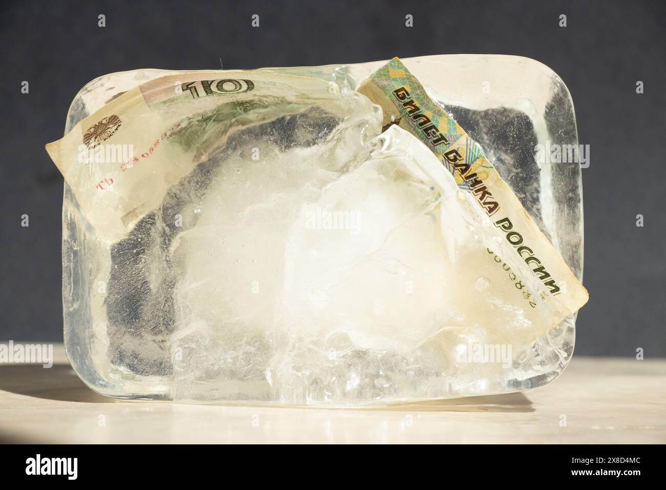 Dieci rubli russi in un cubo di ghiaccio da vicino, soldi russi congelati, sanzioni Foto Stock