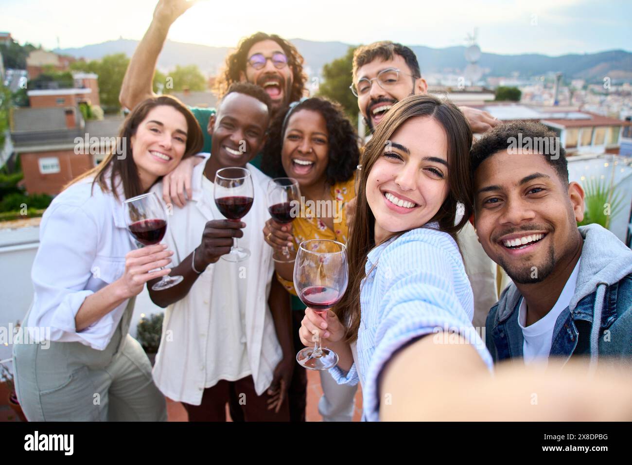 Gruppi diversi amici che si divertono al party sul tetto. Bella donna che prende selfie al momento del barbecue. Foto Stock