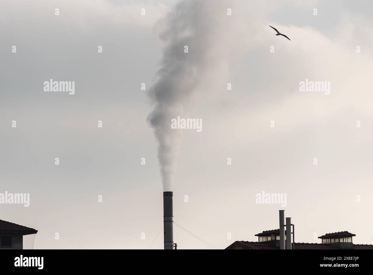 Contesto industriale con camino fumante. Foto Stock