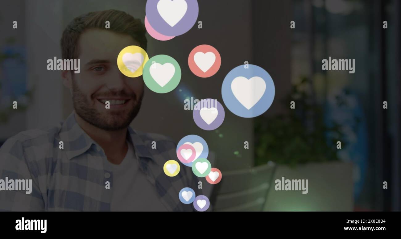 Immagine di icone del cuore sull'uomo caucasico che beve caffè e usa lo smartphone a casa Foto Stock